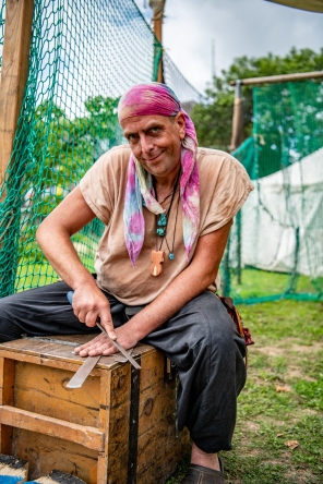 Mann sitzt auf einer Kiste und schleift Metall