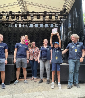 Gruppenbild vor der Bühne und Junge hält Heimatpreis hoch 