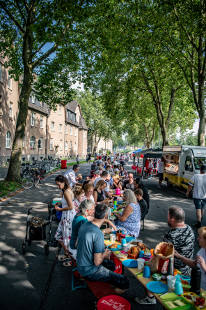 Menschen sitzen an einer langen Reihe von Tischen