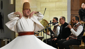 Mann tanzt im Vordergrund und ein Chor singt im Hintergrund