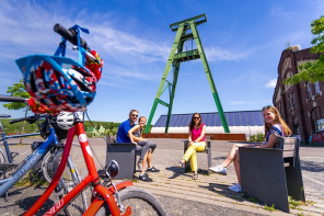 Radfahrer sitzen vor der alten Zeche in Lohberg auf einer Bank
