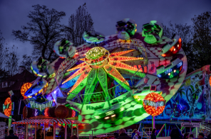 ein drehendes buntes Fahrgeschäft zur Martini Kirmes 2023 vor dunklem Hintergrund