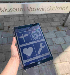 BIPARCOURS-Startseite auf einem iPad vor dem Eingangsschild zum Museum Voswinckelshof BIPARCOURS-Startseite auf einem iPad vor dem Eingangsschild zum Museum Voswinckelshof