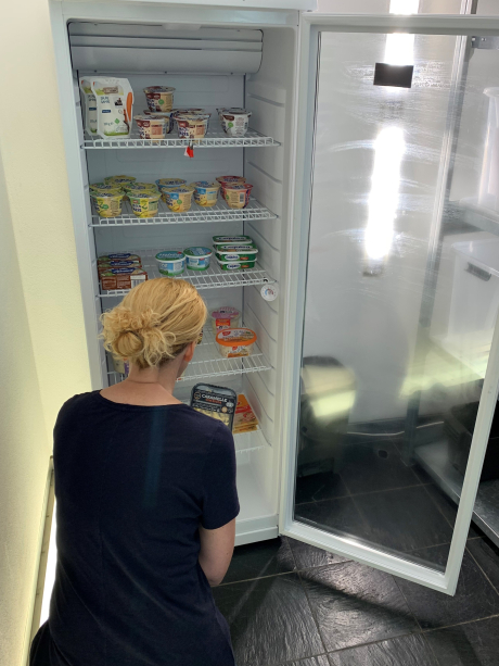 Kühlschrank des Fairteilers im Museum Voswinckelshof Frau kniet vor dem Kühlschrank des Fairteilers im Museum Voswinckelshof und sieht sich die Nahrungsmittel an - Bild vom 17.07.2024