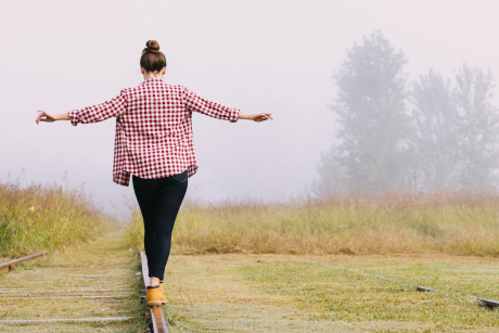 Eine Frau balanciert auf Gleisen in der Natur Eine Frau balanciert auf Gleisen in der Natur
